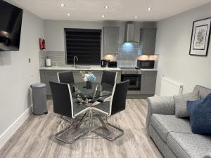 a living room with a glass table and a kitchen at Edward Place Luxury Hot Tub Apartments in Blackpool