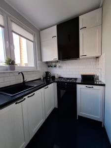 a kitchen with white cabinets and a black counter top at Apartament Spokojny Nad Jeziorem in Sztum +5 photos