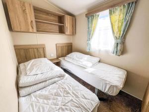 Dos camas en una habitación pequeña con ventana. en Great Caravan For Hire By The Beach In Norfolk, By Hunstanton Beach Ref 13005L, en Hunstanton