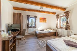 a bedroom with a bed and a desk and a television at Penzion Studánka, Klíny in Klíny