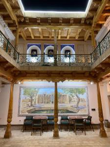 a room with tables and chairs and a painting on the wall at Mukhlisabegim Hotel in Bukhara