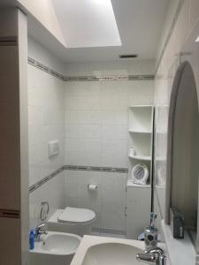 a white bathroom with two sinks and a toilet at Zanella House in Quartu SantʼElena +10 photos