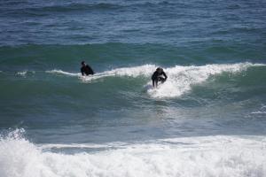 two people riding a wave on surfboards in the ocean at Hotel Cleopatra in Chorefto