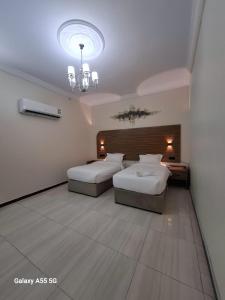 um quarto de hotel com duas camas e um lustre em نسيم الفجر للشقق المخدومة em Jidá