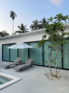 a patio with two chairs and an umbrella and a tree at LAILA Villas in Koh Samui 