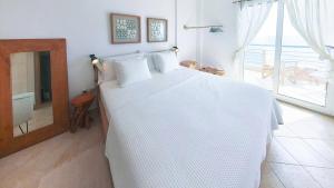 a bedroom with a white bed and a large window at Villa Horizontes 1 in Possidi