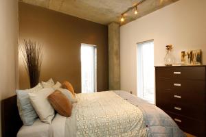 a bedroom with a bed and a dresser and two windows at Résidences Université du Québec in Quebec City