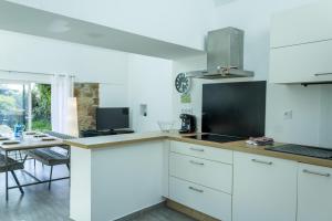 a kitchen with white cabinets and a table with a laptop at Ty Eol - WiFi - Authentique in Camaret-sur-Mer