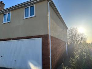 a building with a white garage door and a brick wall at Flat At 34 in Street