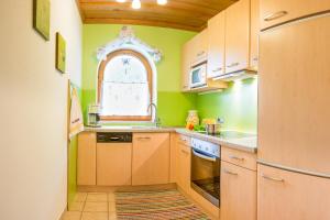 cocina con paredes verdes, armarios de madera y ventana en Haus Larcher, en Neustift im Stubaital