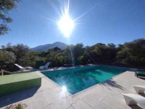 a swimming pool with the sun in the sky at Secretos del quebracho in Capilla del Monte