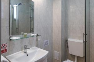 a bathroom with a sink and a toilet and a mirror at Pensiunea EVIA CORBU in Corbu