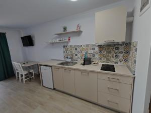 a kitchen with white cabinets and a sink and a table at Pensiunea EVIA CORBU in Corbu +40 photos