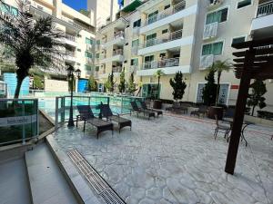 a patio with benches and tables in a building at Apartamento 207 varias piscinas in Bombinhas