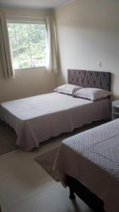 two beds in a bedroom with a window at Casa Vista da Pedra in Domingos Martins