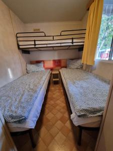two beds in a small room with a window at Mobile Home Emma in Lido di Dante