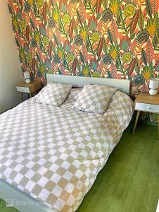 a bed with a checkered blanket in front of a wall at Superbe duplex cœur de ville 3 étoiles in Jonzac