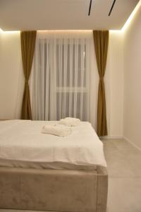 Una cama blanca en una habitación con ventana. en Luxory Apartaments, en Kosovo Polje