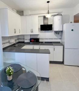 a kitchen with white cabinets and a table and a refrigerator at Newly renovated apartment in Garrucha +6 photos