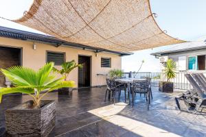 Un patio con una mesa y sillas bajo una sombrilla. en La Villa Vétiver, en Saint-Joseph