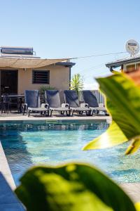 una piscina con sillas y una mesa frente a una casa en La Villa Vétiver, en Saint-Joseph