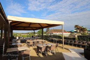 a patio with tables and chairs under a large umbrella at Mobil home 4 à 6 pers camping 5 étoiles proche Deauville in Saint-Arnoult