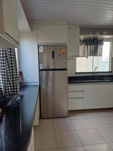 une cuisine avec un réfrigérateur en acier inoxydable et des armoires blanches dans l'établissement Casa de Praia com piscina - Porto de Sauipe, à Porto do Sauipe 13 autres photos