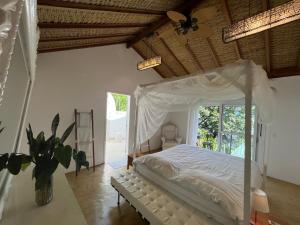 a bedroom with a canopy bed and a window at Beira Mar Ilha Guest in Ilhabela