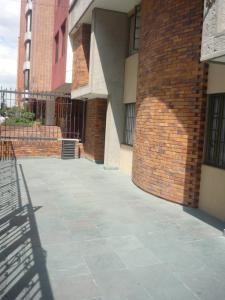 a building with a brick wall and a sidewalk at Hotel Casa La Riviera in Bogotá