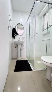 a white bathroom with a sink and a shower at Apartamento Aconchegante, Edifício Frente Mar in Balneário Camboriú
