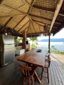 a wooden table and chairs on a deck with a kitchen at Beira Mar Ilha Guest in Ilhabela