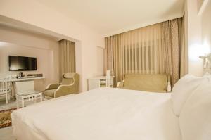 a hotel room with a large white bed and a desk at Cimenoglu Hotel in Denizli