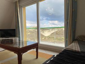 a room with a glass table and a large window at Escapade Sarah, appartement duplex in Fort-Mahon-Plage