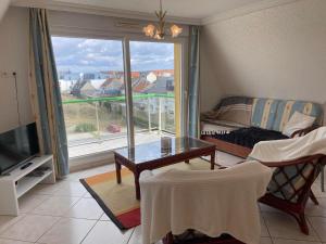 a living room with a table and a couch and a window at Escapade Sarah, appartement duplex in Fort-Mahon-Plage
