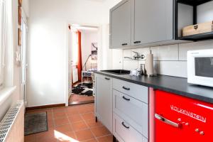 a kitchen with white cabinets and a red appliance at Kleines Apartment in der City in Walsrode