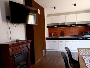a kitchen with a fireplace and a flat screen tv at Sielski Zakątek in Srokowo