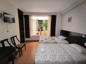 a bedroom with two beds and a desk and a window at La Lisera Suite Residencial in Tacna