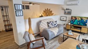 Una sala de estar con un sofá y un televisor. en PoolHouse EstrelasDourada ALVOR, en Alvor