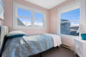 a bedroom with a bed and two windows at Sweet Maine Cottage in Camp Ellis in Saco