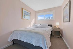 a white bedroom with a bed and a window at Sweet Maine Cottage in Camp Ellis in Saco