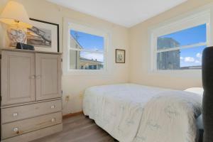 a bedroom with a bed and a dresser and two windows at Sweet Maine Cottage in Camp Ellis in Saco +19 photos