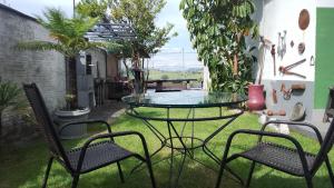 a patio with a glass table and chairs on the grass at Casa com vista exuberante in Pouso Alegre