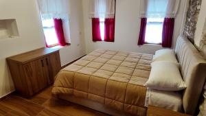 a bedroom with a large bed and two windows at Suite of Bazaar in Gjirokastër