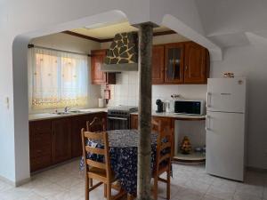 a kitchen with a table and a white refrigerator at Paraíso Açoreano Guest House in Achada