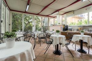 um restaurante com mesas e cadeiras brancas e janelas em Hotel Center 3 em Roma
