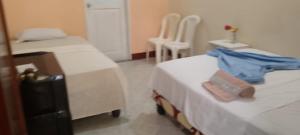 a room with two beds and two white chairs at Hostal La GRAN Familia in Manta