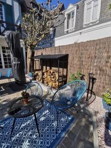 a patio with two chairs and a table and a fire place at Villa normande - Les Crapauds Fous - proximité Centre Ville et Plage in Deauville