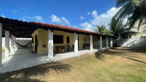 a yellow house with a patio and palm trees at Casa do Arnaldinho in São Miguel dos Milagres