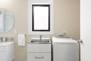 a white bathroom with a sink and a mirror at Central Family Home 5 min to CBD! in Gisborne