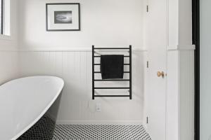 a white bathroom with a bath tub and a towel rack at NEW - Farm House Near Town! in Gisborne +36 photos